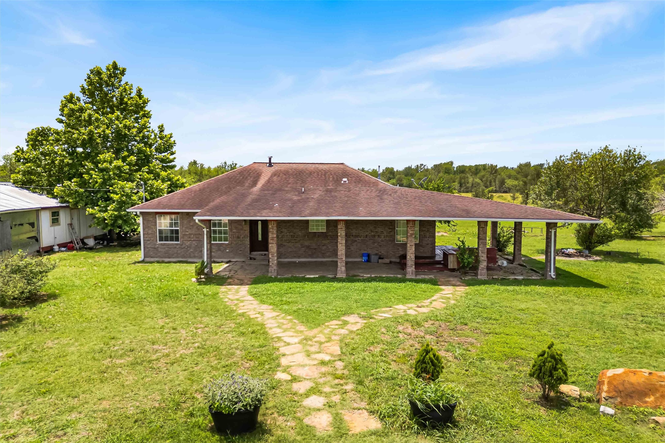 Rear view of house with a yard, a shingled roof, a patio area, and brick siding