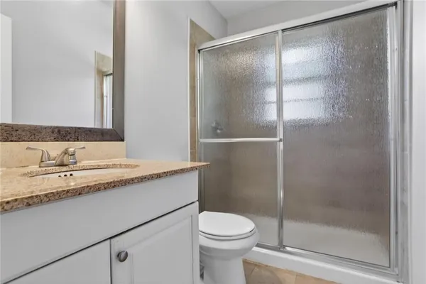 a bathroom with a granite countertop sink toilet and shower