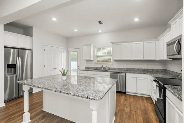 a kitchen with kitchen island granite countertop a stove sink and refrigerator