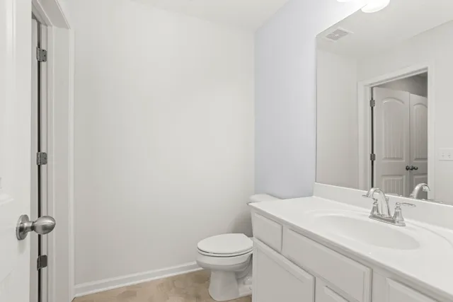 a bathroom with a toilet sink vanity and mirror