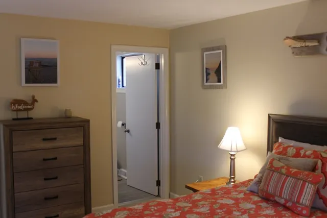a bedroom with a bed and a lamp on dresser