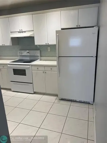 a white refrigerator freezer and a stove sitting inside of a kitchen