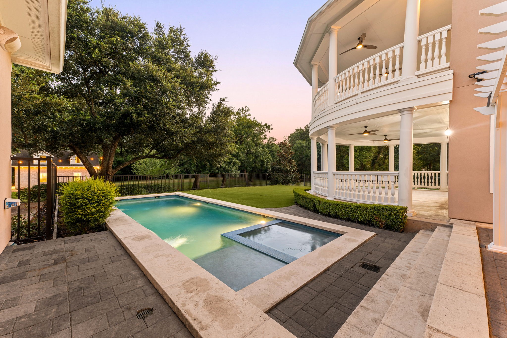 6039 Franz Road Katy, TX 77493 - Photo 36 of 49 The spa sits just off the main pool, both illuminated at dusk beneath the veranda's soft glow — a private oasis framed by mature trees.