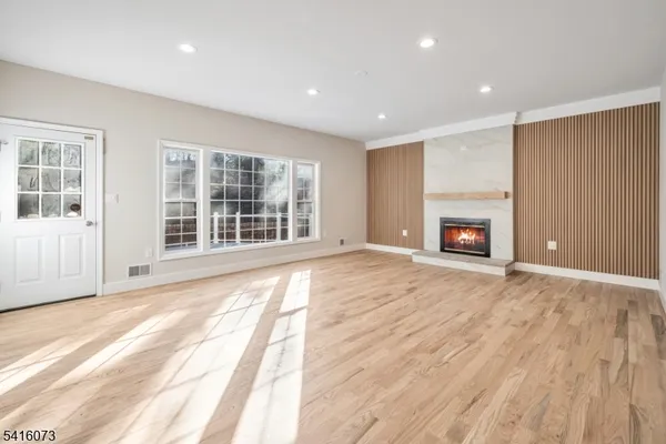 an empty room with wooden floor fireplace and windows