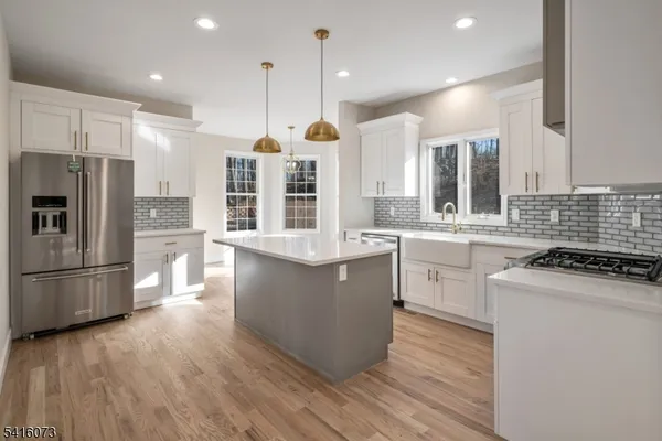 a kitchen with a refrigerator a sink and wooden floor