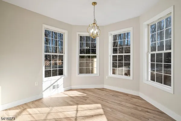 a view of an empty room with windows and chandelier