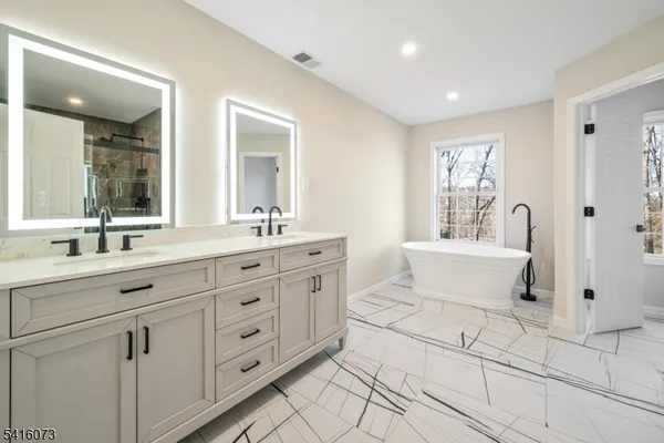 a spacious bathroom with a double vanity sink a mirror and a bathtub
