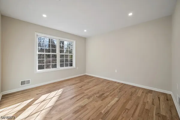 a view of an empty room with wooden floor and windows