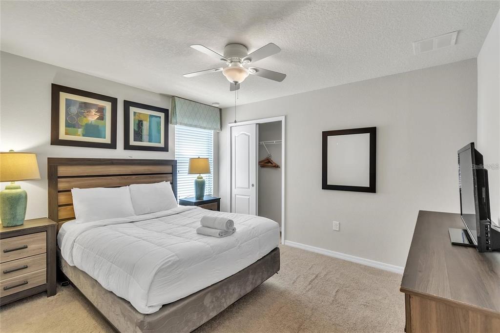 8916 Rhodes Street Kissimmee, FL 34747 - Photo 14 of 34 a bedroom with a large bed and a flat tv screen on dresser