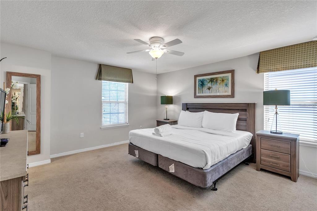 8916 Rhodes Street Kissimmee, FL 34747 - Photo 16 of 34 a spacious bedroom with a bed and a chandelier