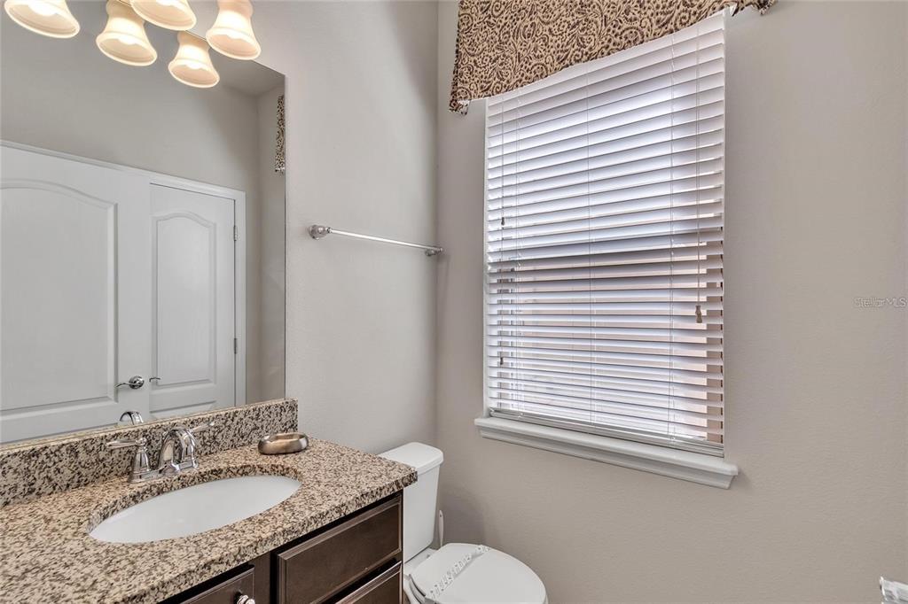 8916 Rhodes Street Kissimmee, FL 34747 - Photo 19 of 34 a bathroom with a granite countertop sink vanity mirror and a toilet