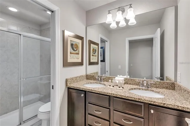 a bathroom with double vanity sinks a toilet a shower a vanity and a mirror