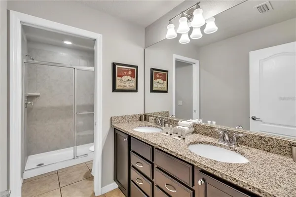 a bathroom with a granite countertop double vanity sink a shower and a mirror