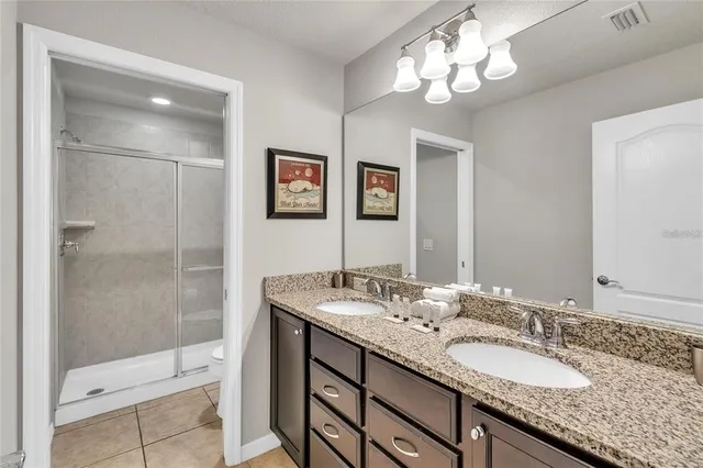 a bathroom with a granite countertop double vanity sink a shower and a mirror
