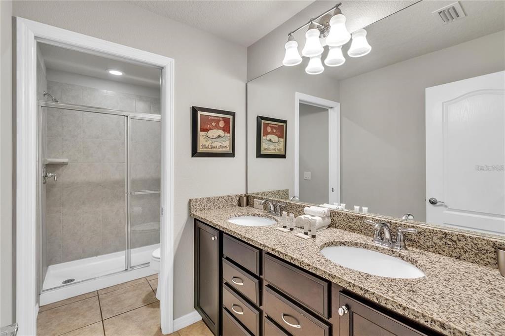 8916 Rhodes Street Kissimmee, FL 34747 - Photo 22 of 34 a bathroom with a granite countertop double vanity sink a shower and a mirror