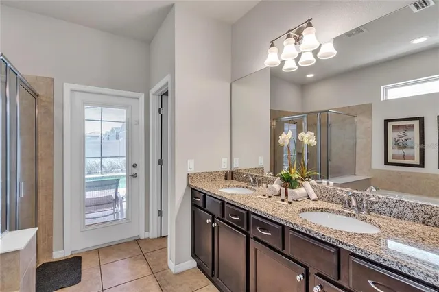 a bathroom with a granite countertop double vanity sink and a mirror