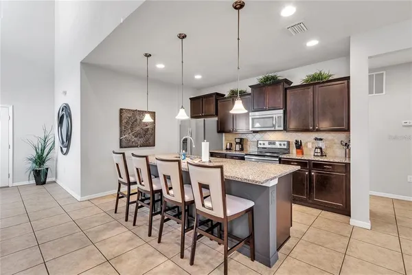 a kitchen with stainless steel appliances granite countertop a stove a sink a microwave a island with a dining table and chairs