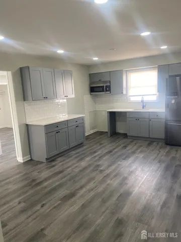 a kitchen with stainless steel appliances wooden floors and white walls
