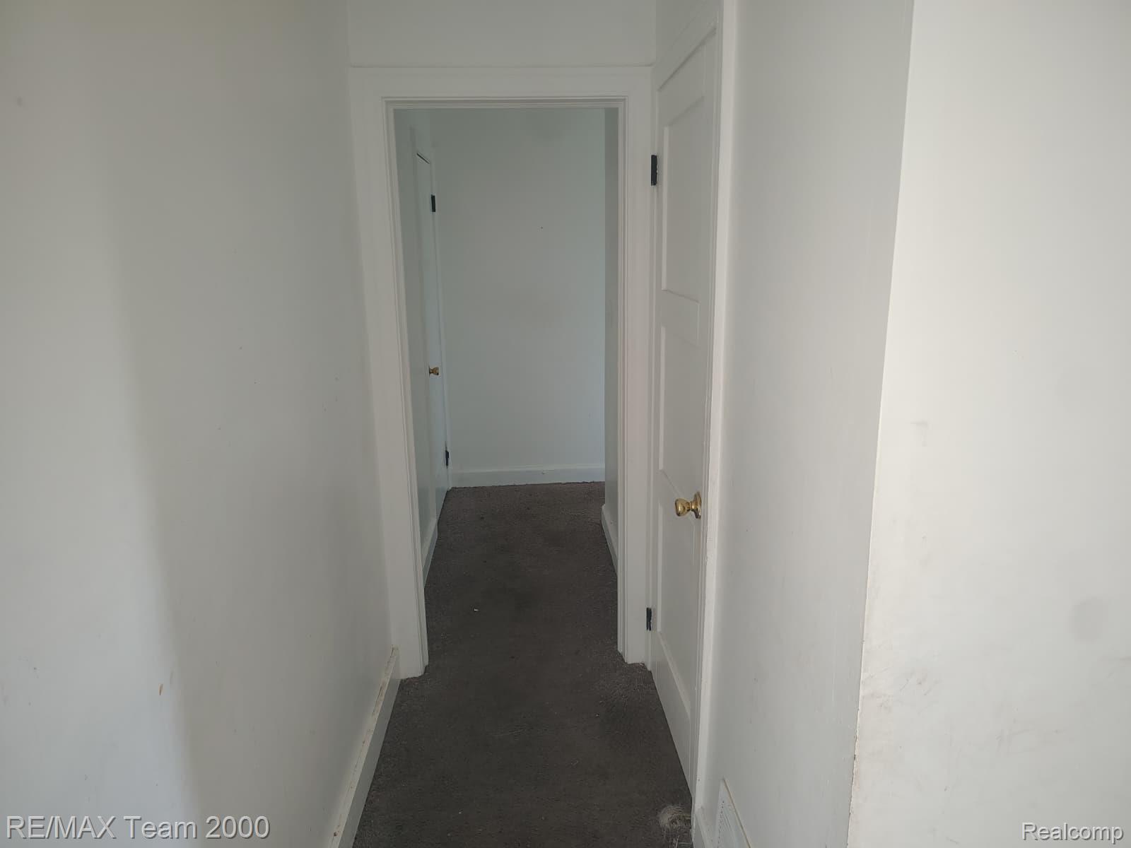8860 Appoline Street Detroit, MI 48228 - Photo 30 of 45 Interior hallway featuring neutral tone walls, dark carpeting, and white trim