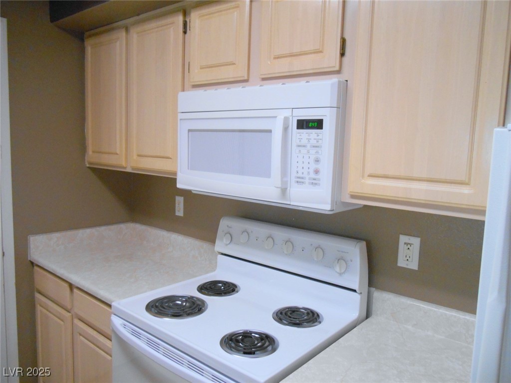 555 East Silverado Ranch Boulevard, Unit 1073 Las Vegas, NV 89183 - Photo 10 of 21 Kitchen featuring white appliances, light countertops, and light brown cabinetry