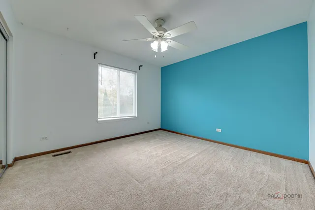 an empty room with windows and ceiling fan