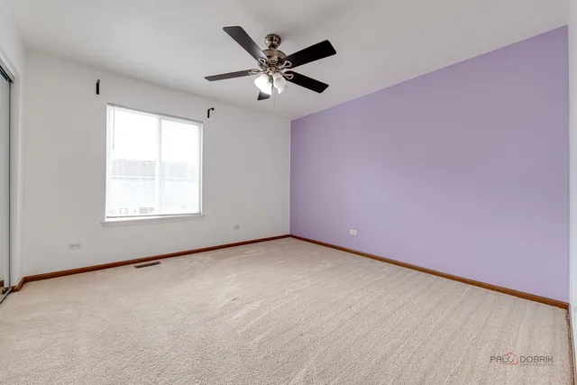 an empty room with ceiling fan and windows