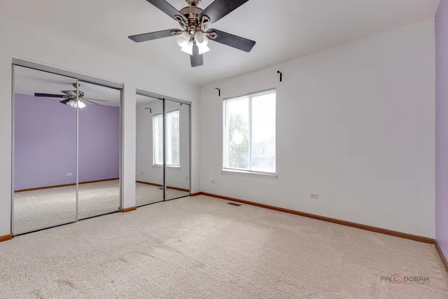 an empty room with chandelier fan and windows