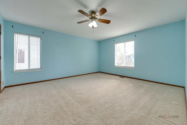 an empty room with windows and chandelier fan