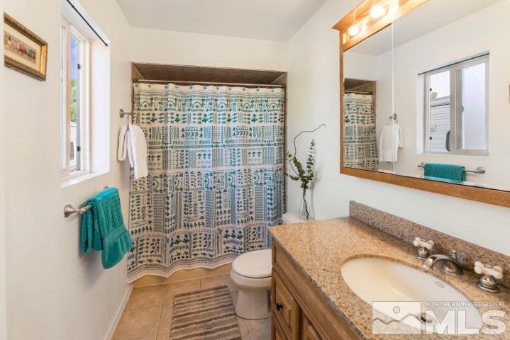 5155 Pasture View Road Reno, NV 89510 - Photo 14 of 21 a bathroom with a granite countertop toilet a sink a shower and a mirror