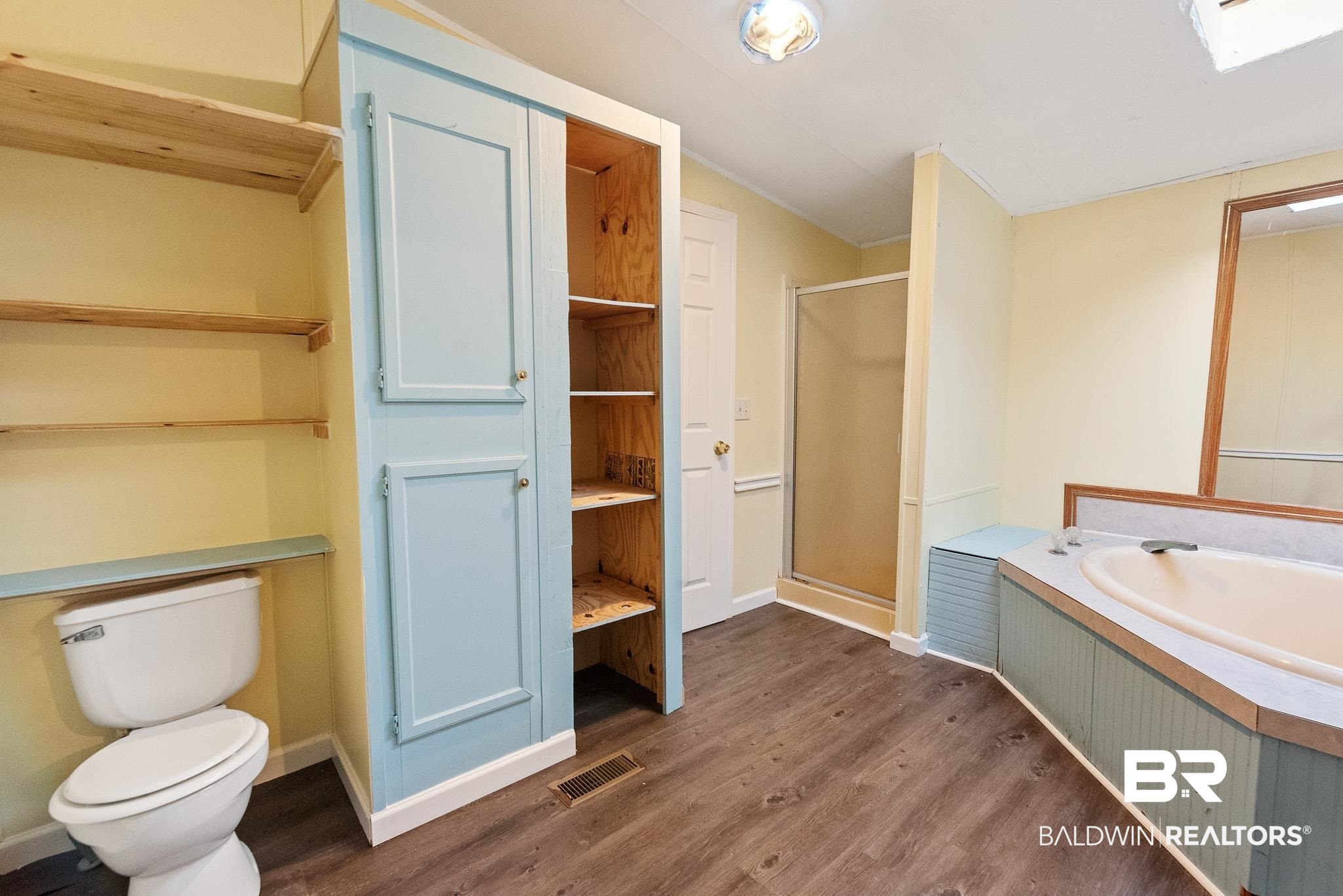 7695 Bermuda Drive Semmes, AL 36575 - Photo 17 of 27 Bathroom with wood finished floors, visible vents, a stall shower, vaulted ceiling, and toilet