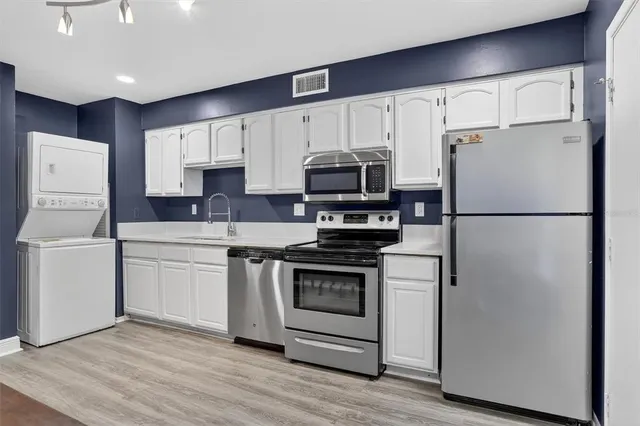 a kitchen with cabinets stainless steel appliances and wooden floor