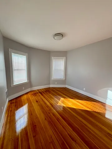 a view of empty room with window and wooden floor