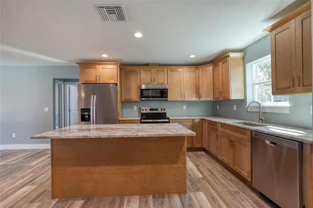 a kitchen with stainless steel appliances granite countertop a stove a sink and a microwave