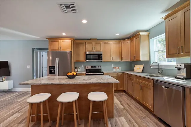 a kitchen with stainless steel appliances granite countertop a kitchen island hardwood floor sink stove and table