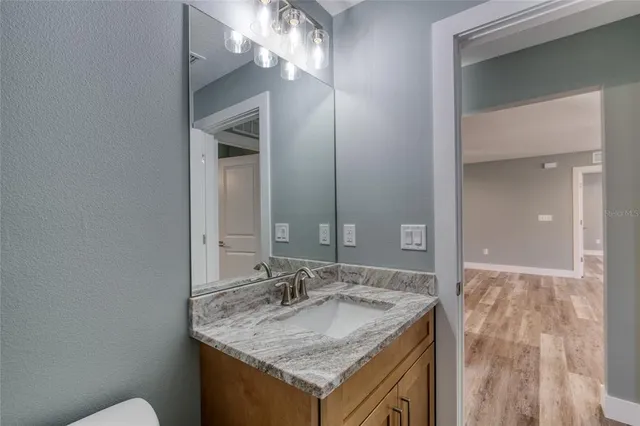 an empty room with wooden floor chandelier fan and windows