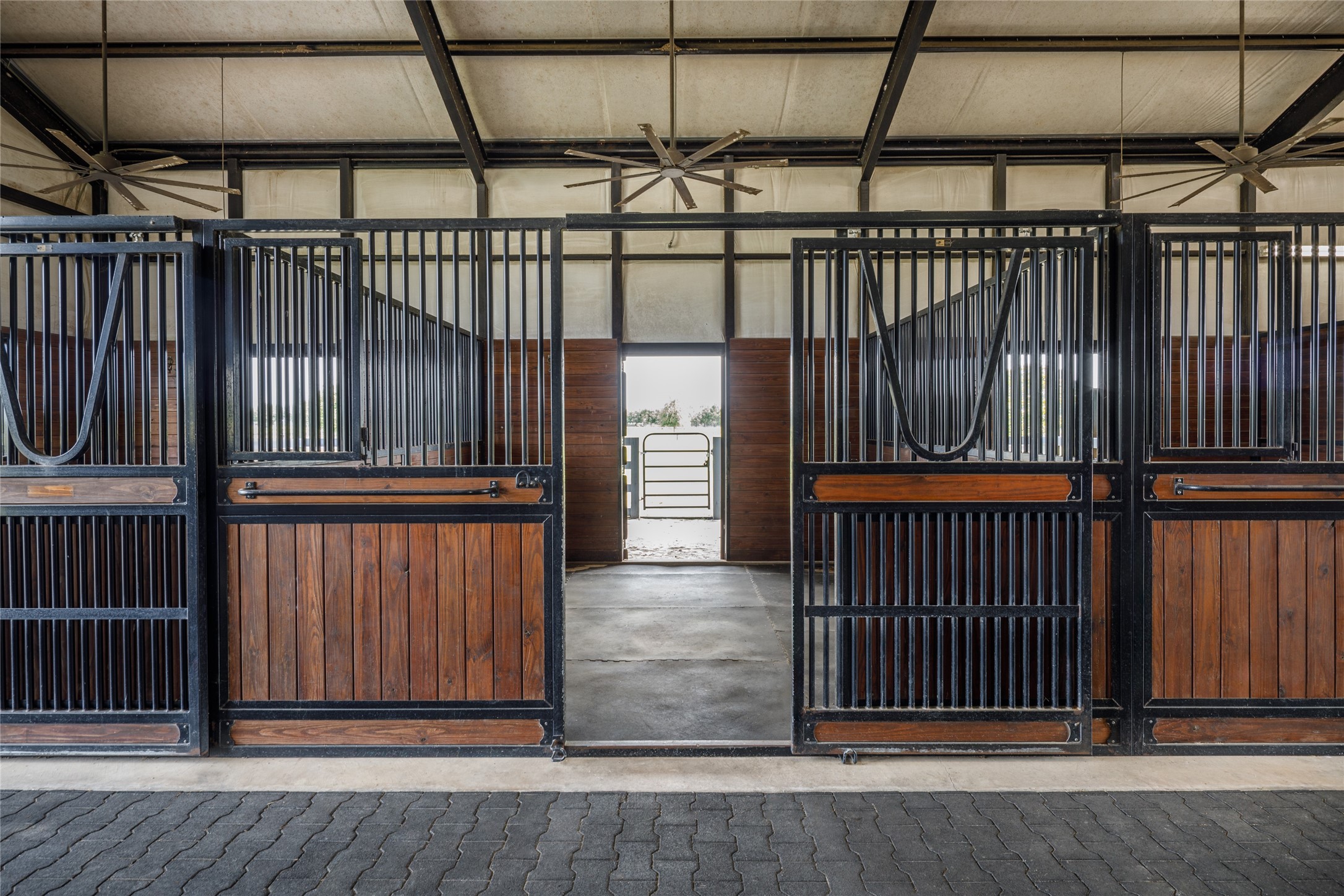 24118 Margerstadt Road Hockley, TX 77447 - Photo 37 of 46 Oversized 14 by 14 stalls, custom wood and metal finishes, and direct access to turnout areas create a barn setup centered around both horse comfort and everyday practicality. The open breezeway design allows the equestrian facilities to function efficiently throughout the seasons.
