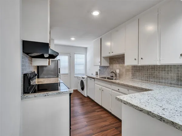 a kitchen with granite countertop a sink stainless steel appliances and white cabinets