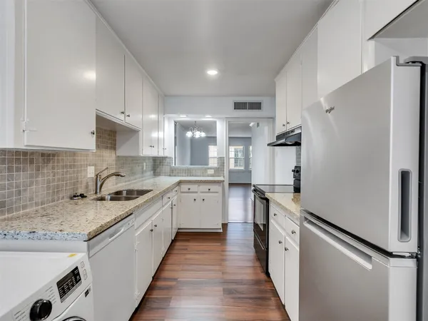 a kitchen with granite countertop kitchen island stainless steel appliances a refrigerator sink and cabinets
