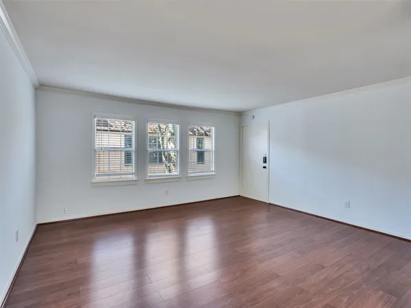 a view of an empty room with wooden floor and window