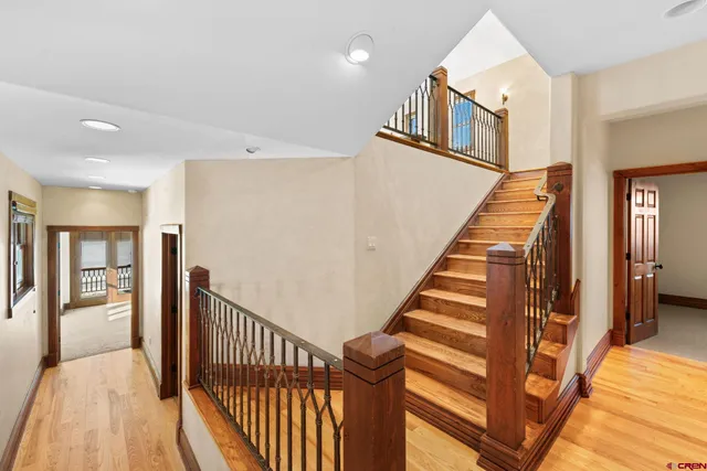 a view of staircase with lots of frames on wall and a dining table