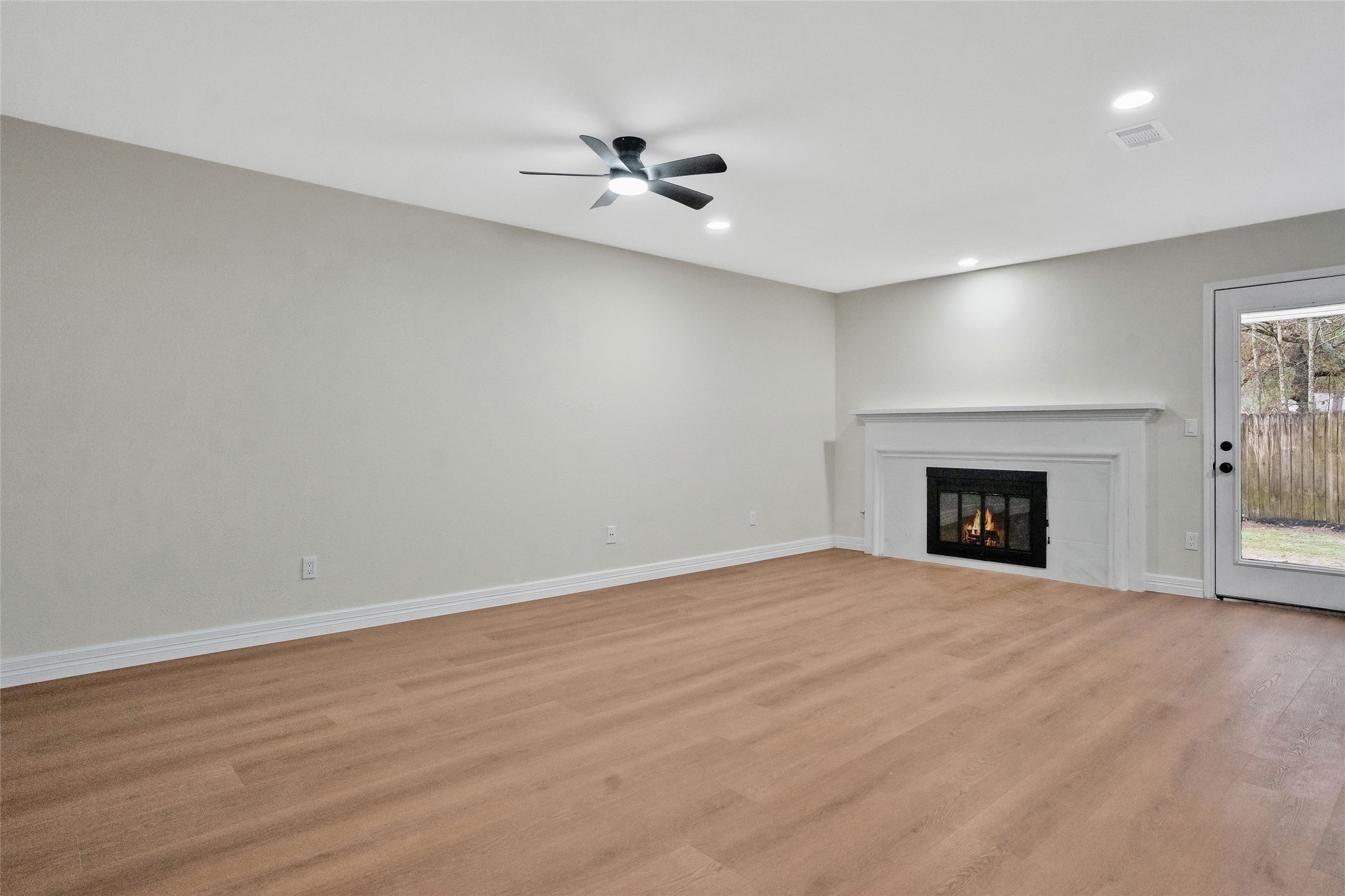 3 Still Corner Place Spring, TX 77381 - Photo 14 of 41 Inviting family room featuring a cozy fireplace, recessed lighting, ceiling fan, and updated LVP flooring, offering a comfortable space for everyday living.