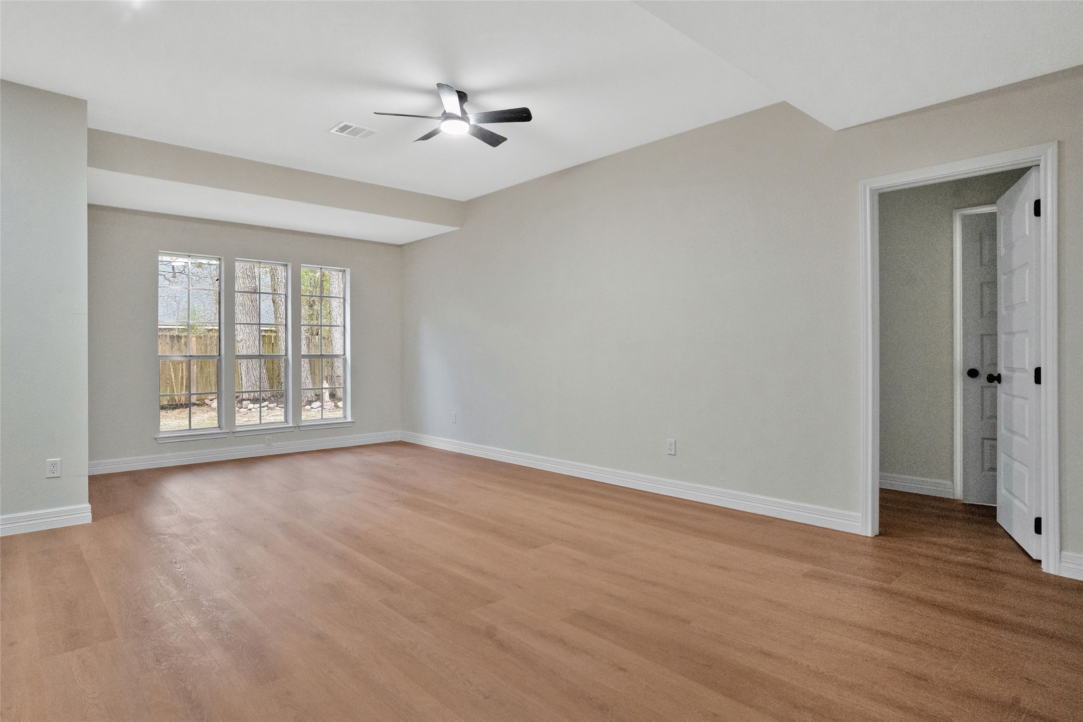 3 Still Corner Place Spring, TX 77381 - Photo 22 of 41 Spacious living room featuring updated flooring, neutral paint tones, vaulted ceiling with ceiling fan, and large windows that bring in abundant natural light.