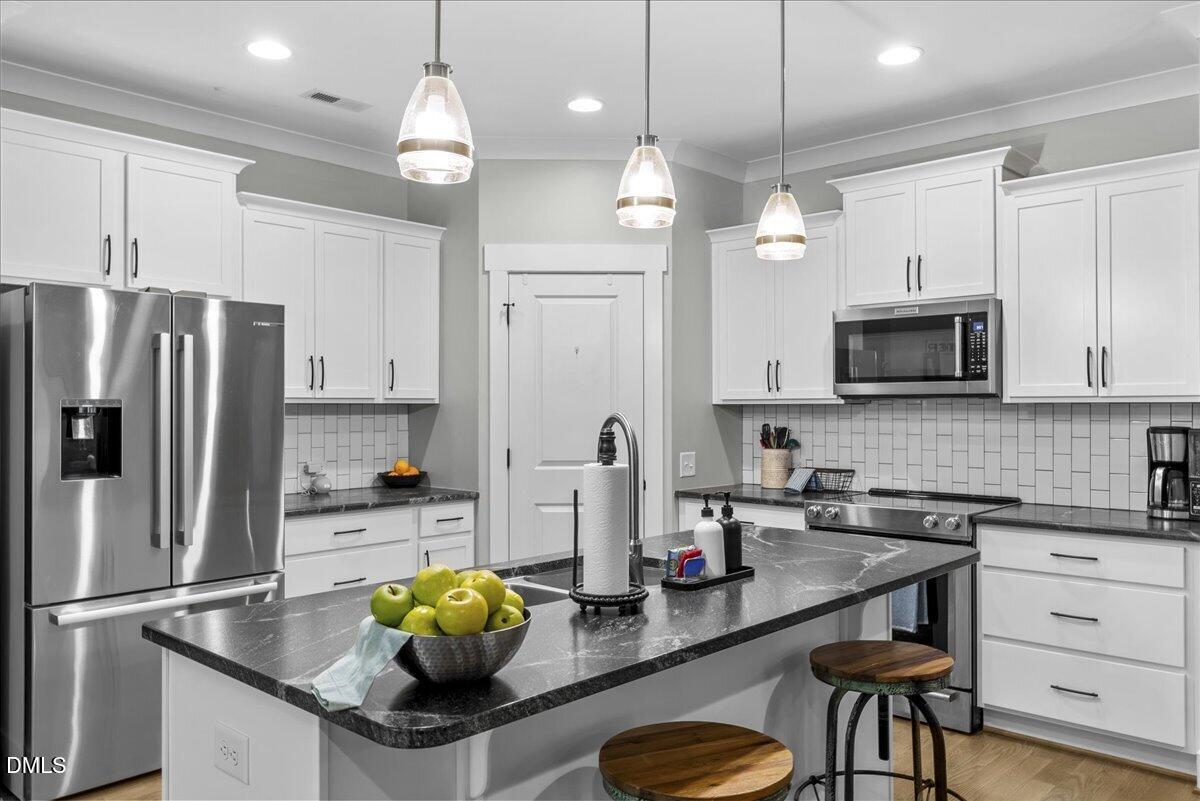 a kitchen with stainless steel appliances granite countertop a sink refrigerator and microwave