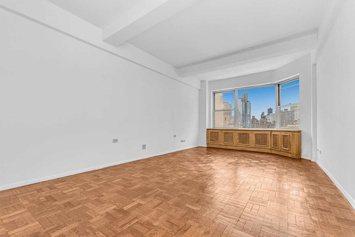 215 East 79th Street, Unit 12B Manhattan, NY 10075 - Photo 6 of 11 a view of an empty room with wooden floor and a window