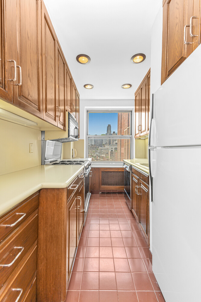 215 East 79th Street, Unit 12B Manhattan, NY 10075 - Photo 8 of 11 a kitchen with stainless steel appliances granite countertop a refrigerator and a sink