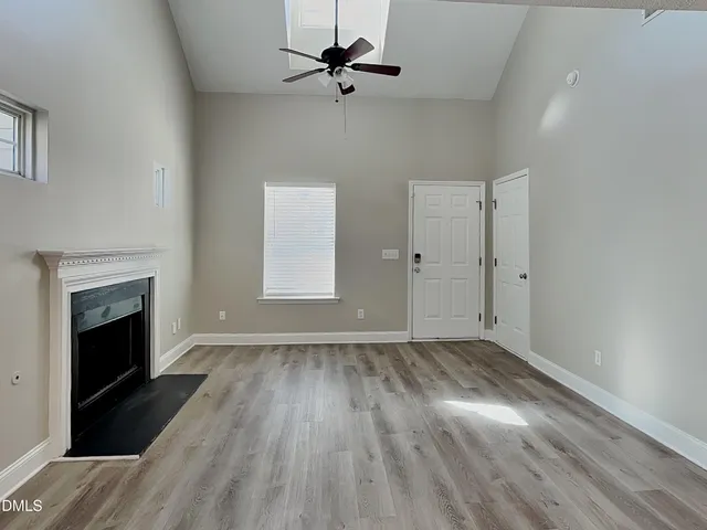 an empty room with wooden floor fireplace and windows