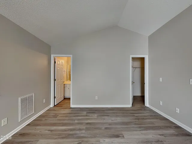 a view of an empty room with wooden floor and closet