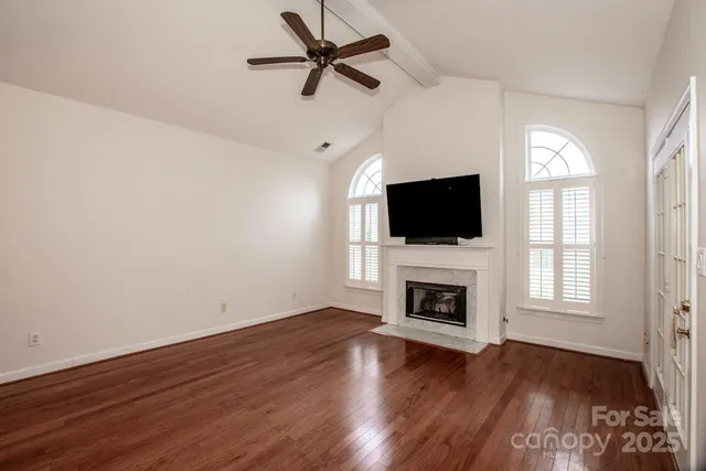 a kitchen with stainless steel appliances granite countertop a sink a stove a refrigerator and white cabinets with wooden floor