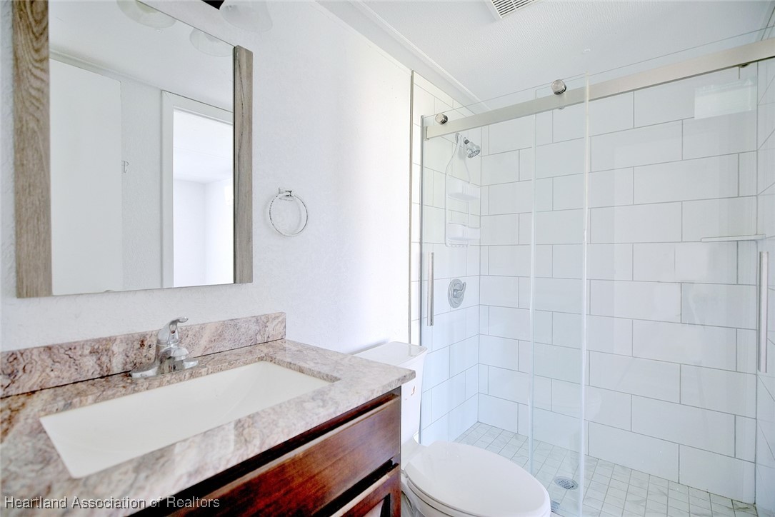 258-264 Griffin Road Wauchula, FL 33873 - Photo 14 of 33 a bathroom with a granite countertop sink toilet a mirror and shower