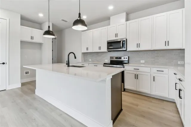 a large kitchen with kitchen island granite countertop a window and white cabinets